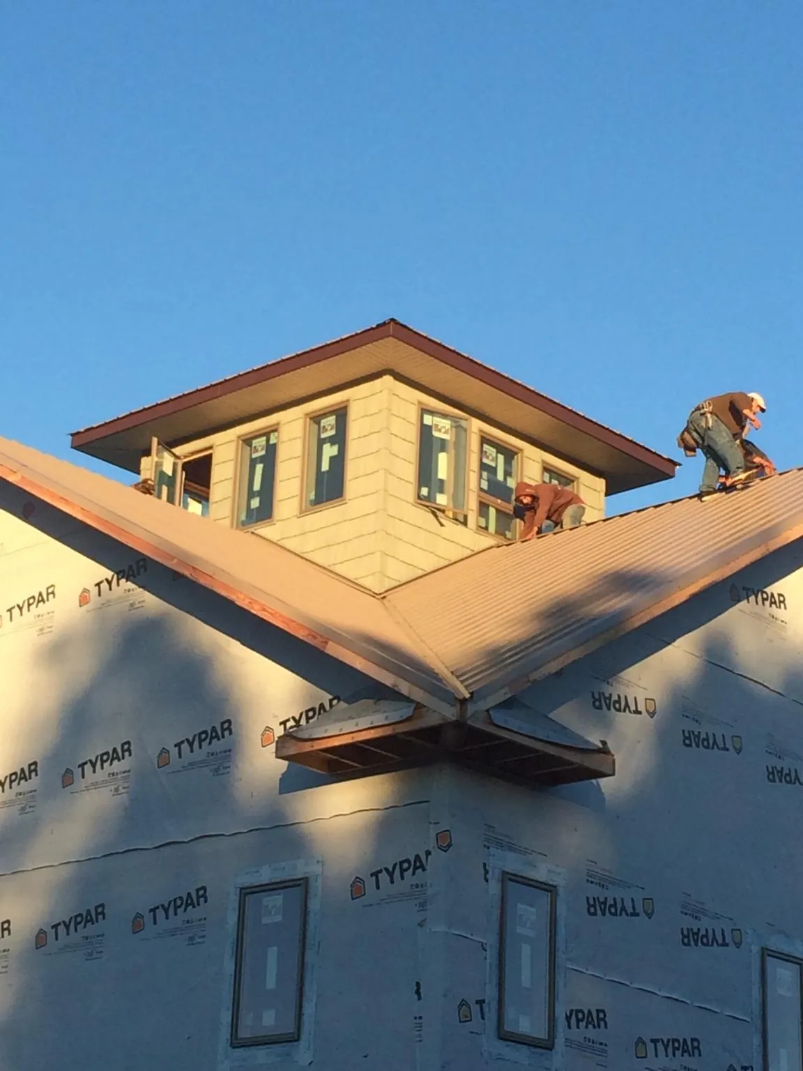 Roofers working around a rooftop cupola on a new metal roof at sunset — Roof Waterproofing in Saint Louis by Roofing Brothers